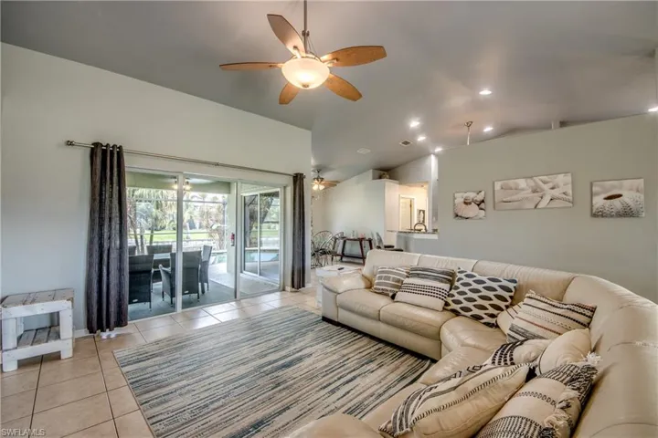 Tiled living room with vaulted ceiling and a ceiling fan