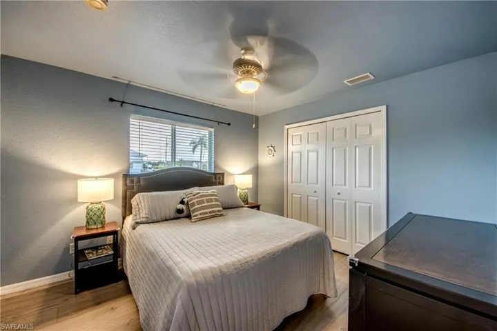 Bedroom with light wood-style floors, a ceiling fan, and a textured wall