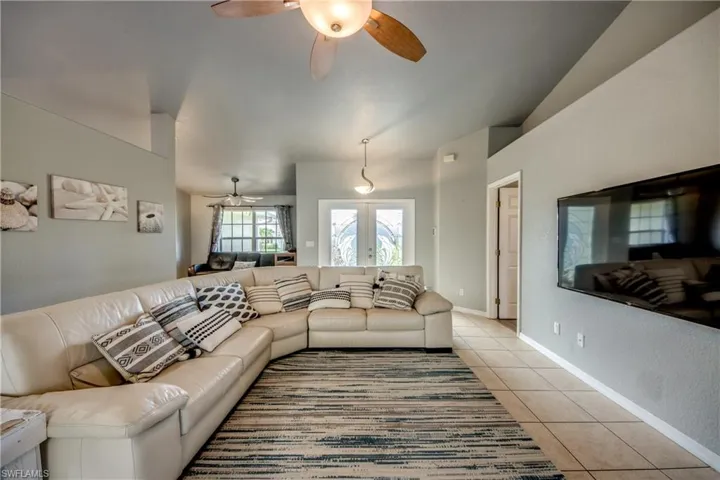 Living room featuring ceiling fan, light tile patterned floors, lofted ceiling, french doors, and recessed lighting