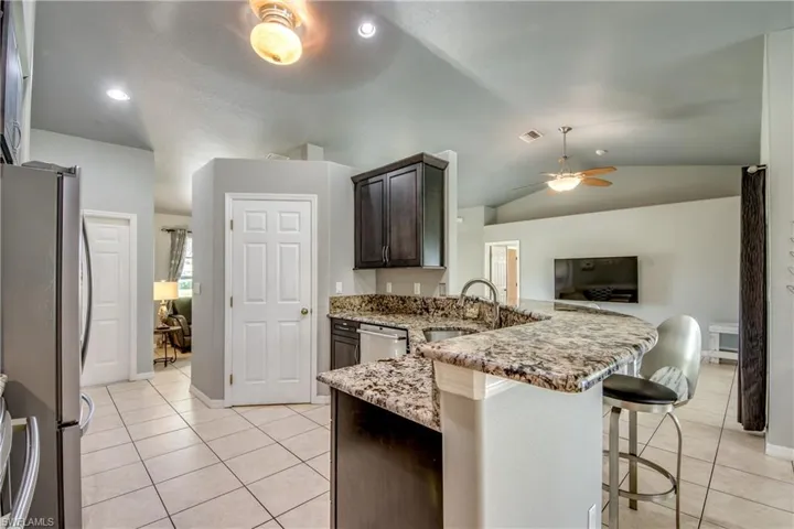 Kitchen with stainless steel appliances, vaulted ceiling, a peninsula, ceiling fan, and dark brown cabinets