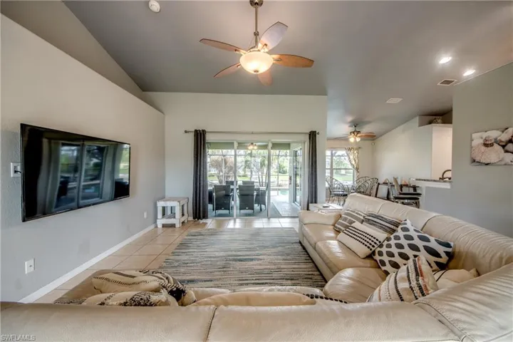 Living room featuring light tile patterned floors, ceiling fan, and vaulted ceiling