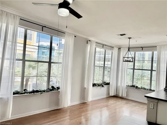 Unfurnished dining area featuring ceiling fan, ornamental molding, and light wood-type flooring