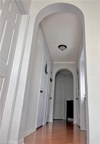 Hall featuring ornamental molding and dark wood-type flooring