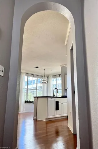 Kitchen featuring pendant lighting, crown molding, white cabinetry, dark hardwood / wood-style floors, and kitchen peninsula