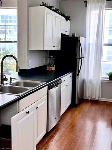 Kitchen featuring sink, hardwood / wood-style flooring, white cabinets, and dishwasher