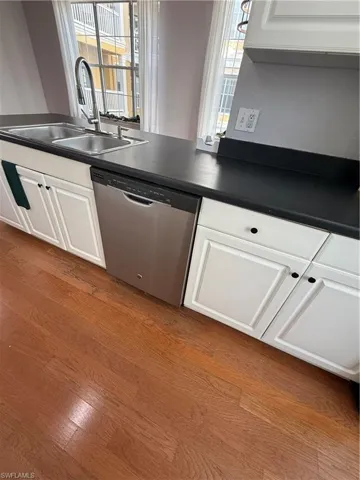 Kitchen with light hardwood / wood-style floors, sink, white cabinets, and dishwasher