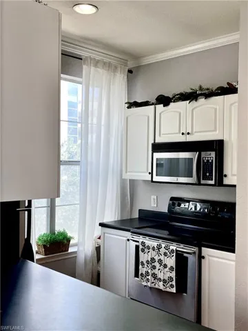 Kitchen with white cabinetry, appliances with stainless steel finishes, ornamental molding, and a textured ceiling