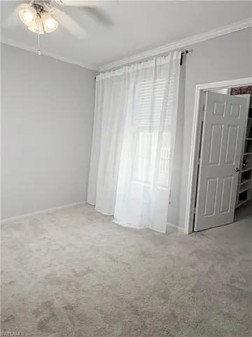 Unfurnished bedroom featuring ceiling fan, carpet flooring, and ornamental molding
