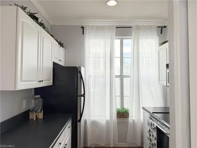 Kitchen featuring electric range, white cabinets, and crown molding