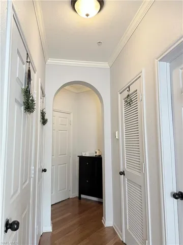 Corridor with dark wood-type flooring and crown molding