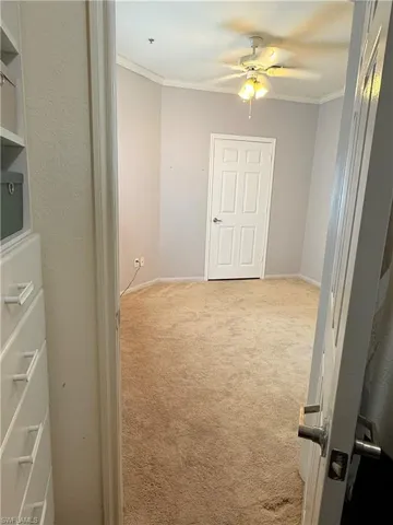 Hallway with light colored carpet and ornamental molding