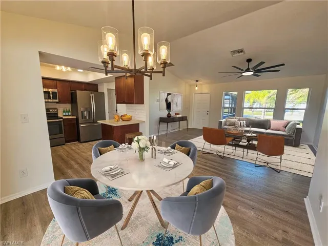 Dining room featuring a ceiling fan, lofted ceiling, dark wood-type flooring, and a chandelier