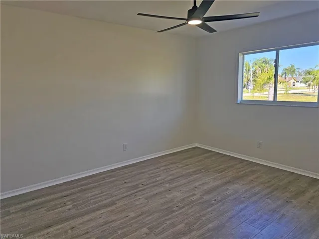Spare room with dark wood-type flooring and ceiling fan