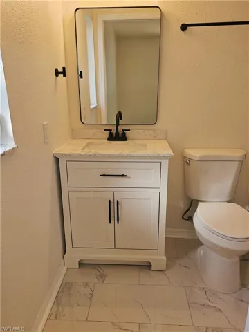 Bathroom featuring a textured wall, vanity, and light marble finish flooring