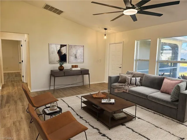 Living area with lofted ceiling, wood finished floors, and ceiling fan
