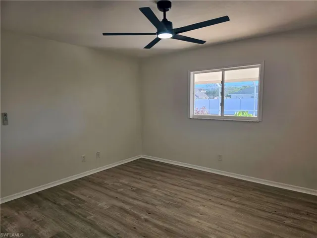 Empty room with dark wood finished floors and a ceiling fan