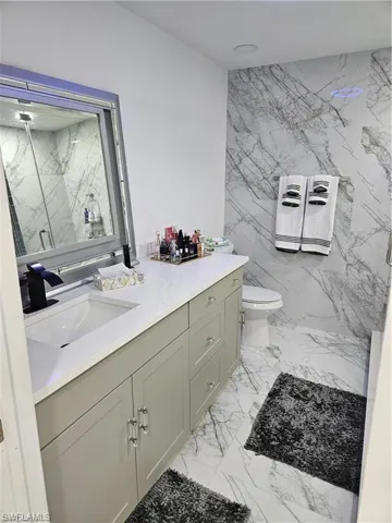 Bathroom featuring vanity, toilet, and a shower with door