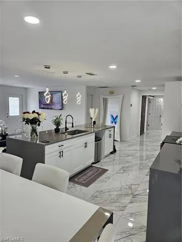 Kitchen featuring white cabinetry, sink, a kitchen island, and hanging light fixtures