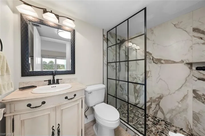 Custom vanity with an undermount sink, black framed mirror, and an updated shower