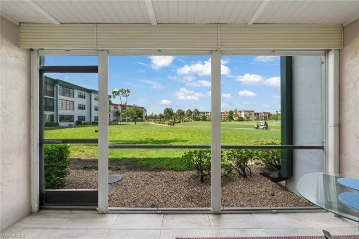 Screened lanai with tile flooring and a view of hole #7 green