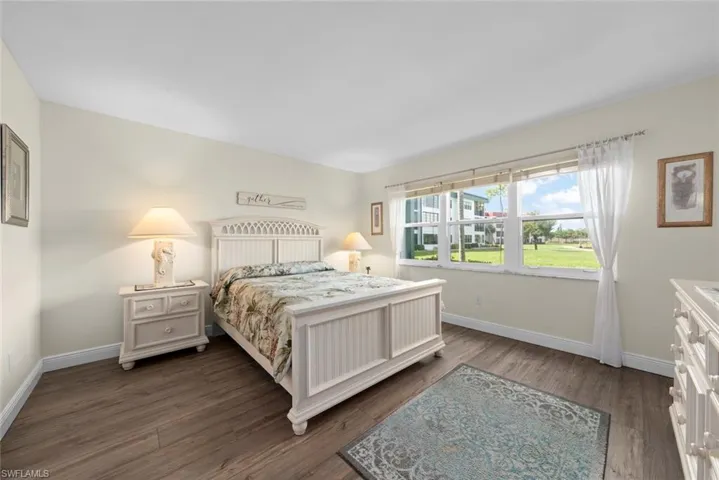 Primary bedroom with luxury vinyl flooring, light-toned walls, and a multi-pane window