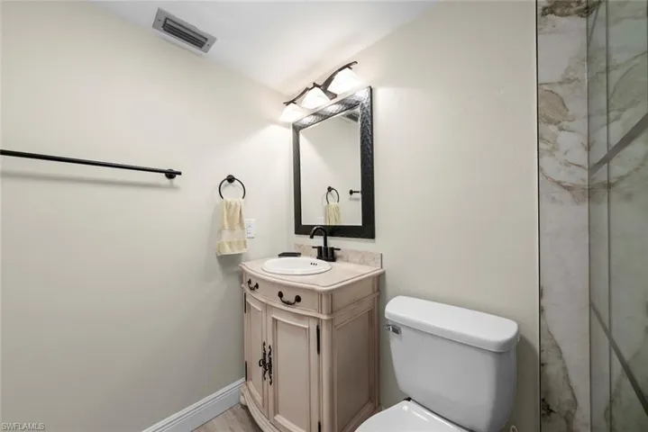 Primary bathroom featuring a vanity with an integrated sink, black hardware, a toilet, and a glass-enclosed shower
