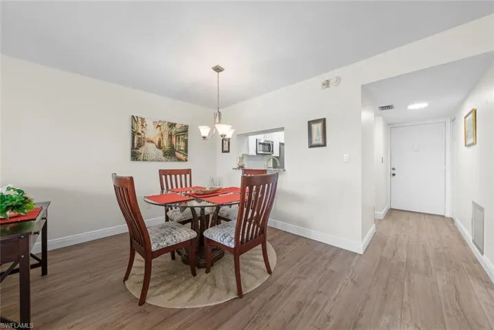 Open-concept dining area featuring a contemporary chandelier and a pass-through window to the kitchen