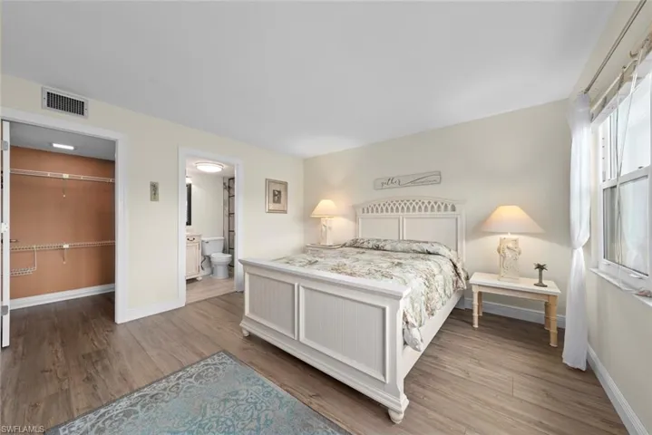 Primary bedroom featuring vinyl flooring, a walk-in closet, and direct access to a full bathroom