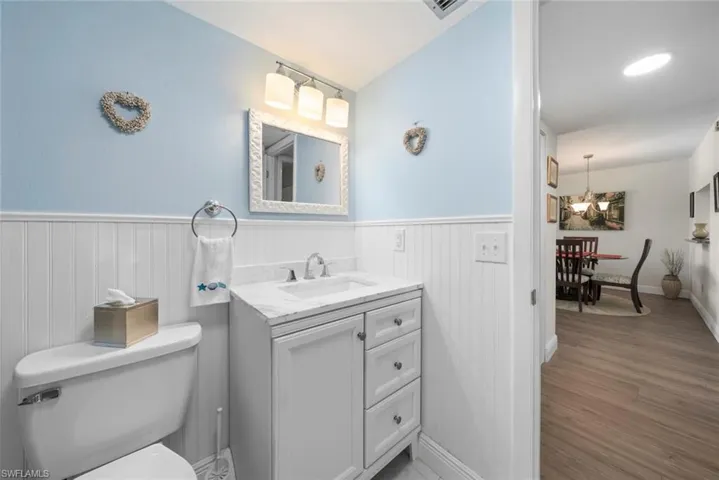 White vanity with a single basin sink and a stone countertop