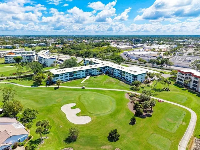 Condo building featuring balconies overlooking the golf course with sand traps and mature trees