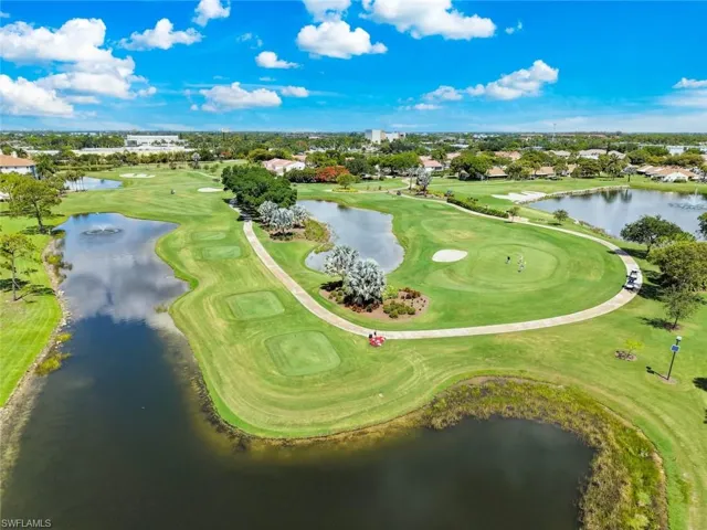Expansive golf course setting featuring multiple greens and a paved cart path