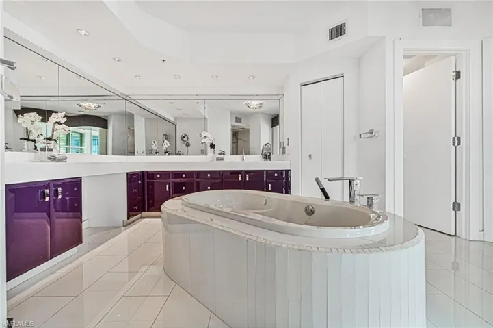 Full primary bath ensuite is complete with a garden soaking tub, light stone rectangular format tile bright flooring, expansive custom modern vanities, and modern decorative andrecessed lighting