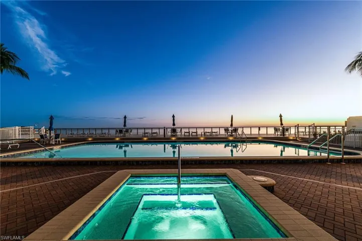 Pool at dusk featuring a community pool and a community hot tub