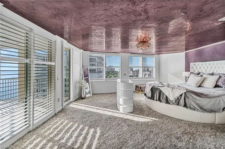 The enormous primary en suite bedroom features 3 walls of glass for stunning views, a built-in modern ‘televator’ in front of the bed and the glamorous chandelier —- all contrasted by richly colored designer plaster ceiling work. A separate seating area and 3 access points out to a private patio balcony create a magical waterfront experience for the owner.