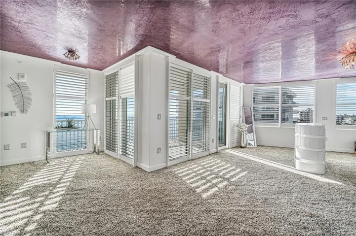 The primary en suite is surrounded by glass and natural light leading out to a private balcony. It is somewhat separated by a seating area at the entry and highlighted by a motion elevator custom cabinet for bedside viewing.