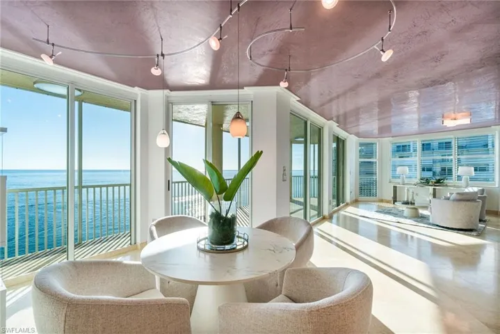 The exclusive PENTHOUSE waterfront dining area feels like a postcard perfect Sunroom highlighted by a rich custom Venetian plaster ceiling,  functional & beautiful contemporary track lighting, a water view, and expansive windows with Southern golf waterfront views in two directions.