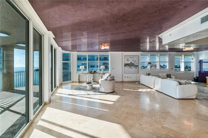 Welcome to the open concept main living area -  grounded with timeless, large format, travertine flooring, and a stunning contrast of Rich eggplant in a plaster ceiling throughout mimicking the painted skies from the sunsets each evening.