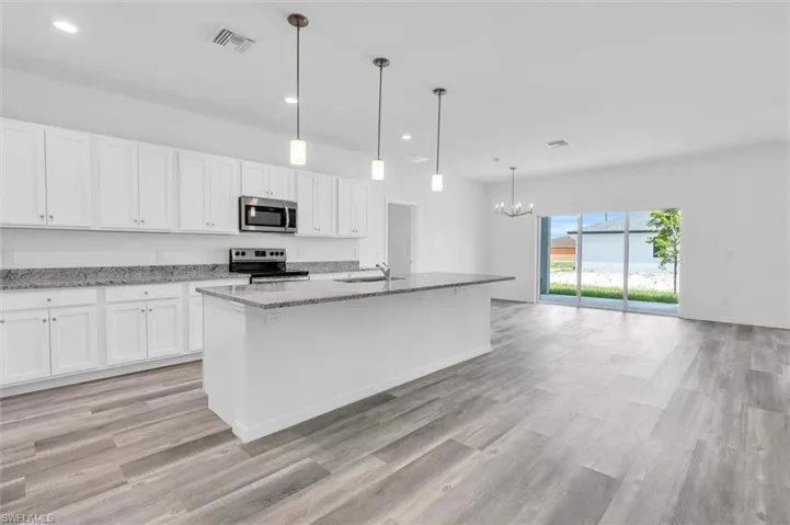 Kitchen featuring stainless steel appliances, a chandelier, light stone countertops, light wood-style flooring, and recessed lighting