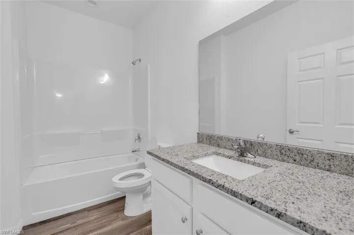 Bathroom with wood finished floors, vanity, and tub / shower combination