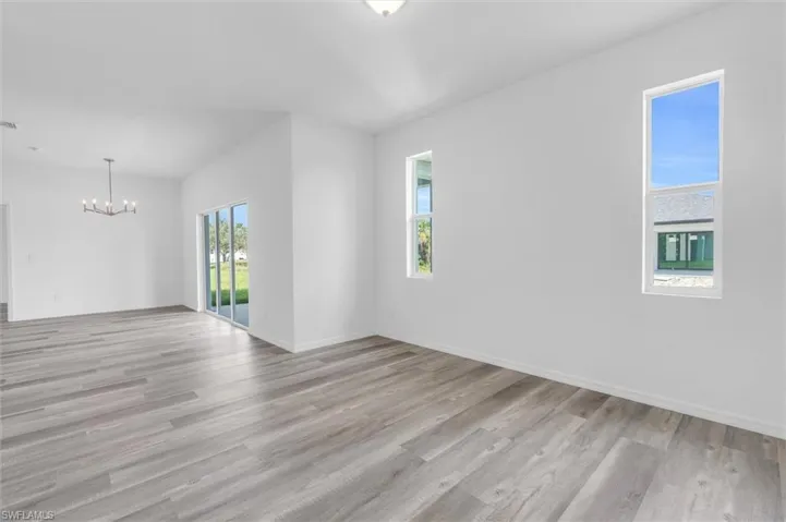 Unfurnished room featuring a chandelier and light wood-style flooring