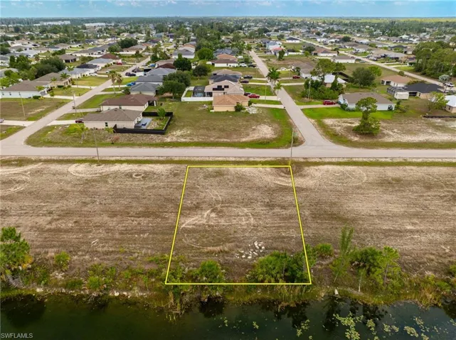 Aerial view of residential area with property boundaries highlighted and a nearby body of water