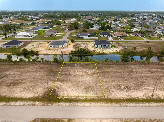 Aerial view of residential area with property parcel outlined and a nearby body of water
