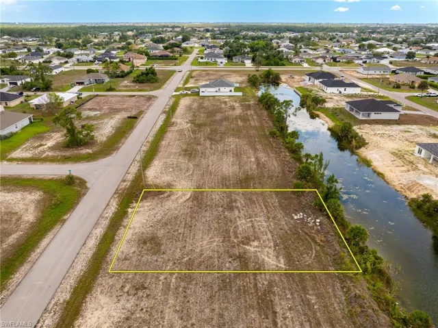 Aerial view of residential area featuring property parcel outlined and a nearby body of water