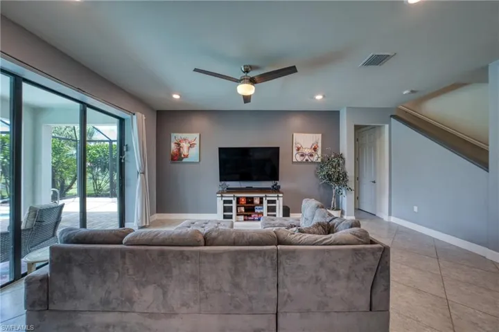 Living room with ceiling fan and light tile patterned flooring