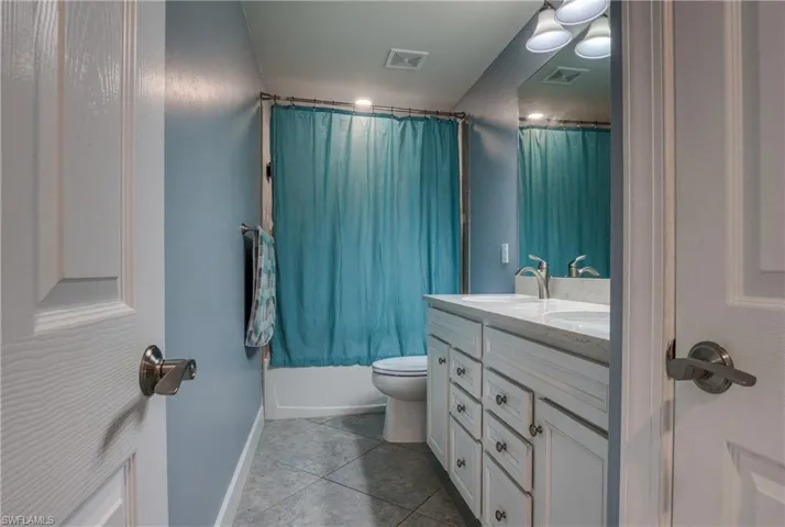 Full bathroom featuring vanity, toilet, tile patterned flooring, and shower / bathtub combination with curtain