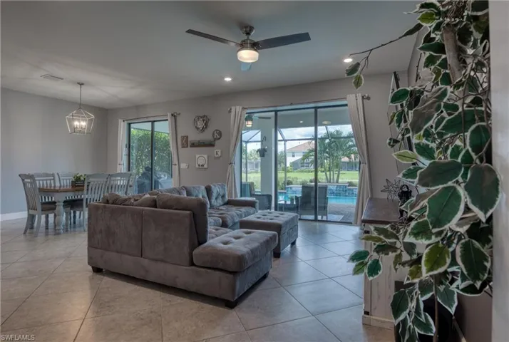 Tiled living room with ceiling fan with notable chandelier