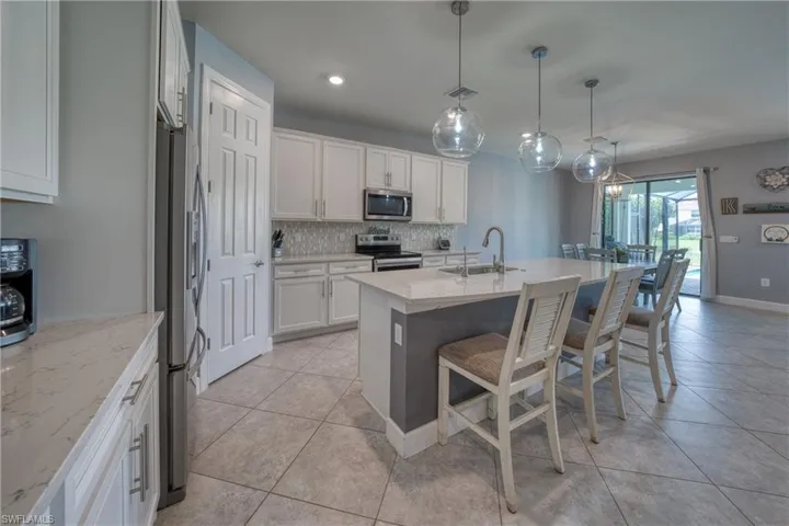 Kitchen featuring stainless steel appliances, light stone counters, sink, and white cabinets