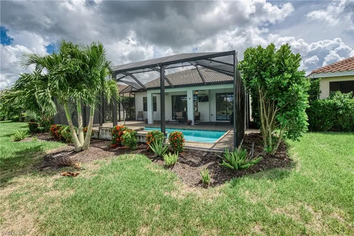 Back of house featuring a yard, glass enclosure, a patio area, and ceiling fan