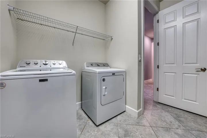 Clothes washing area with light tile patterned floors and washer and dryer