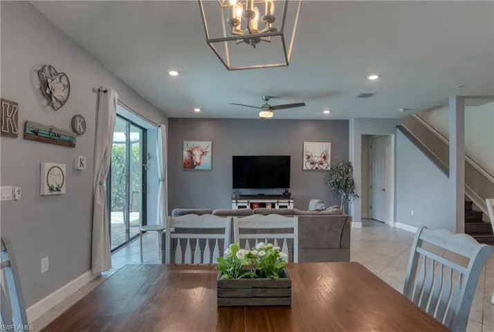 Dining space with light tile patterned floors and ceiling fan with notable chandelier